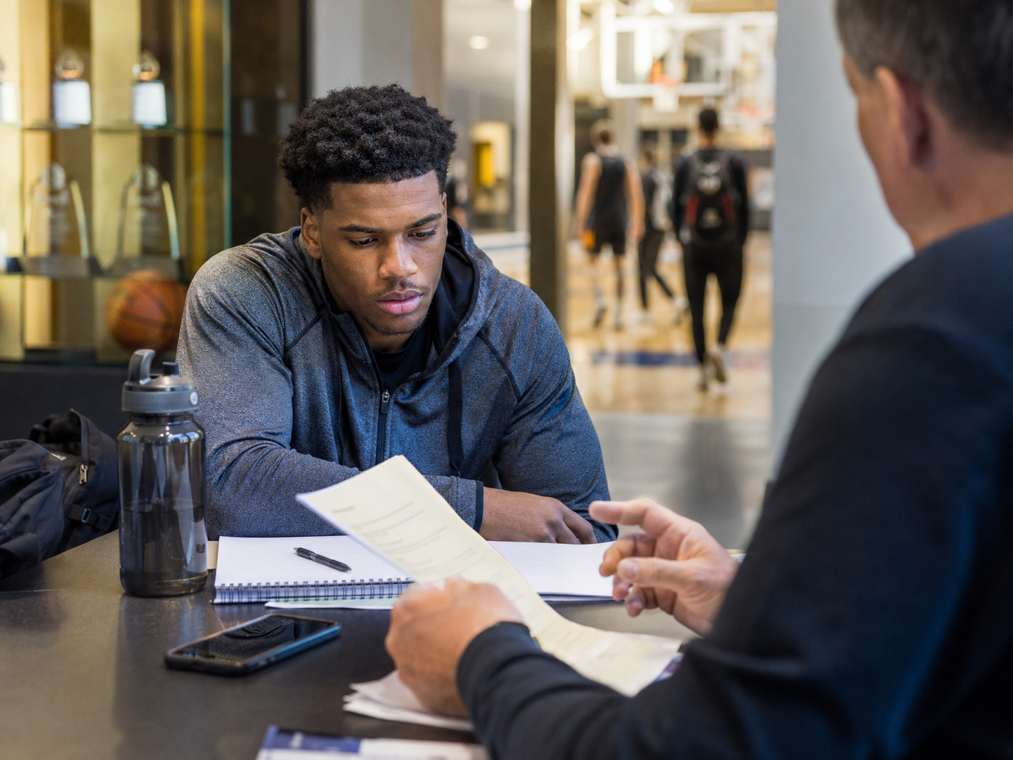 College sports compliance binders and athletic equipment sit on a conference table.
