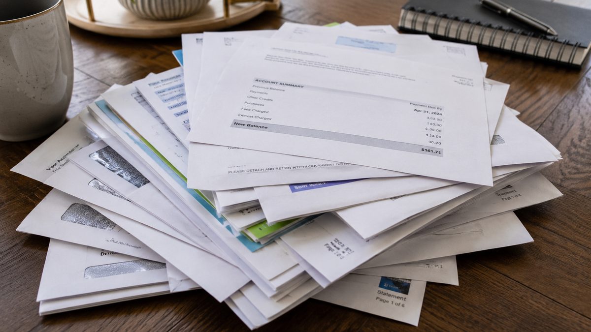 Household bills, a receipt and a calculator on a kitchen table.