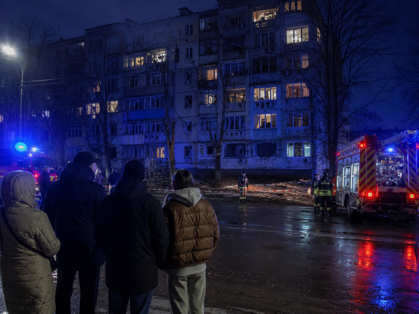 Emergency responders stand near damaged residential buildings after an overnight attack in Ukraine.