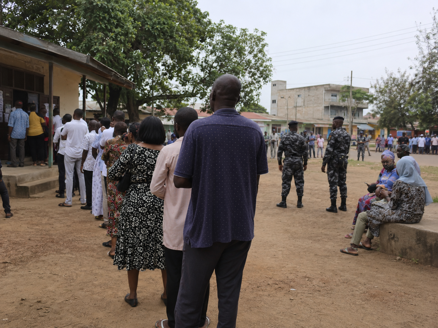 Voters wait outside a polling place as security personnel stand nearby.