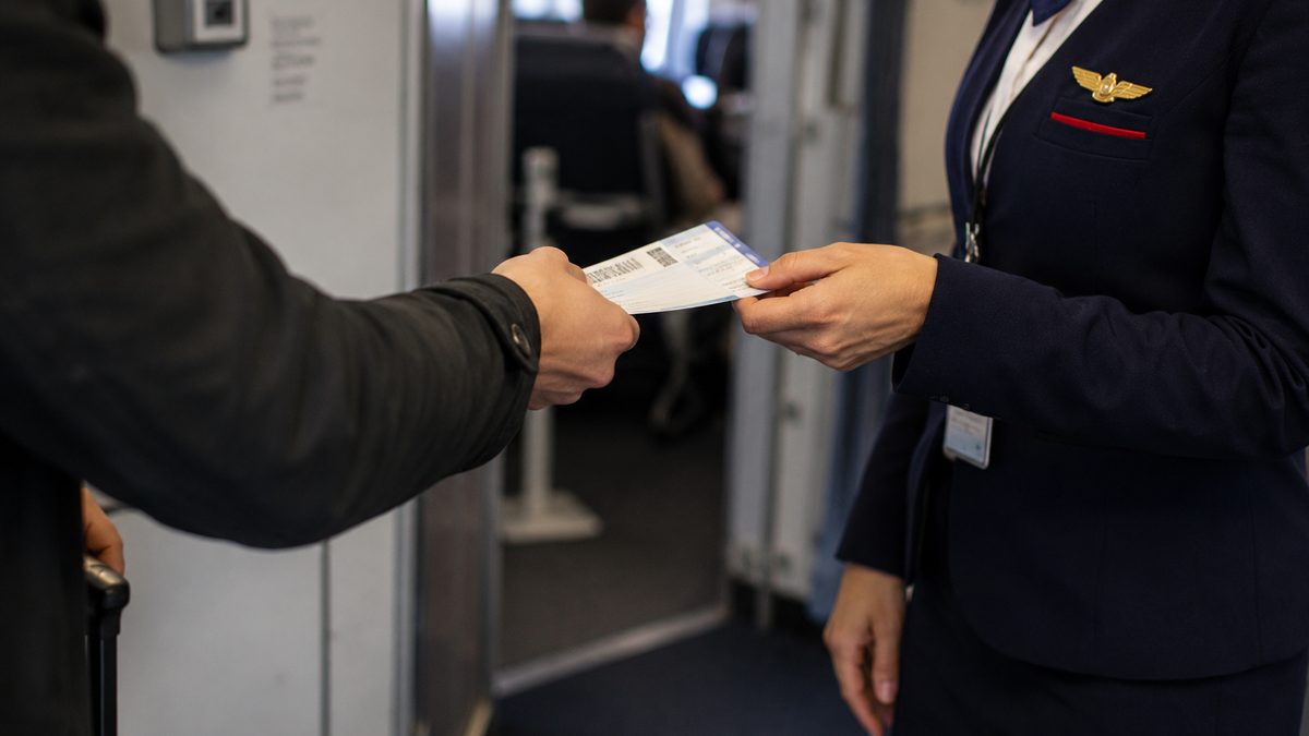 A traveler reviews airline information on a phone beside a suitcase.