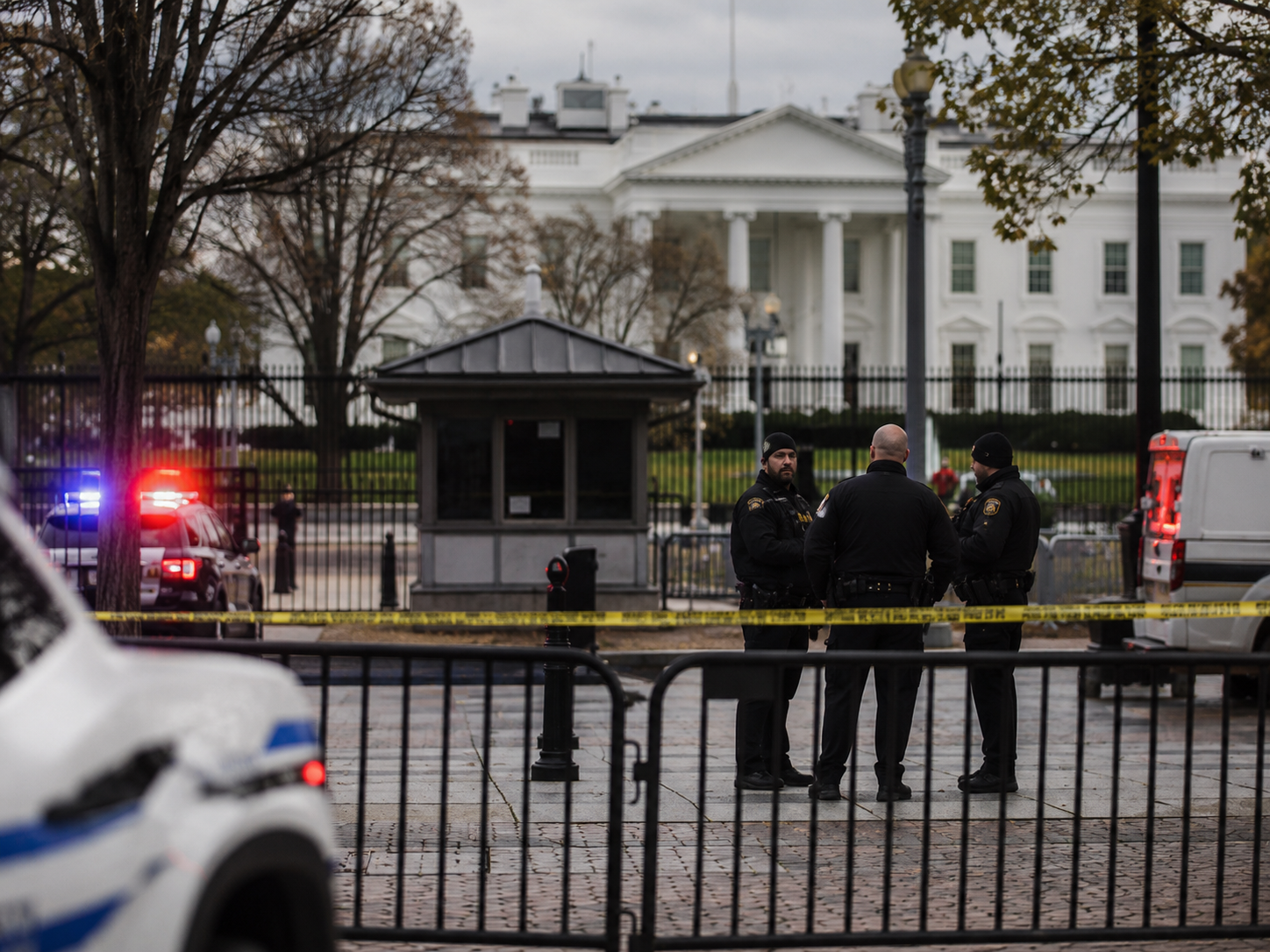 Law enforcement vehicles and officers secure a street near a federal building perimeter.