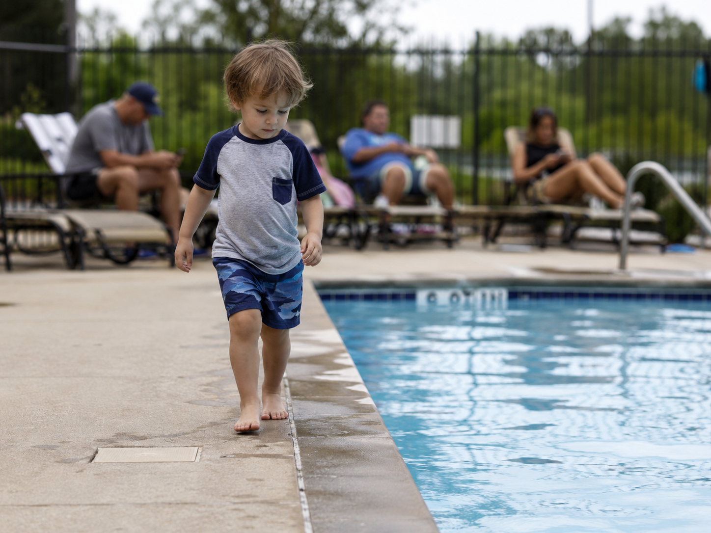 A quiet backyard pool edge with water and a drain area in soft focus.