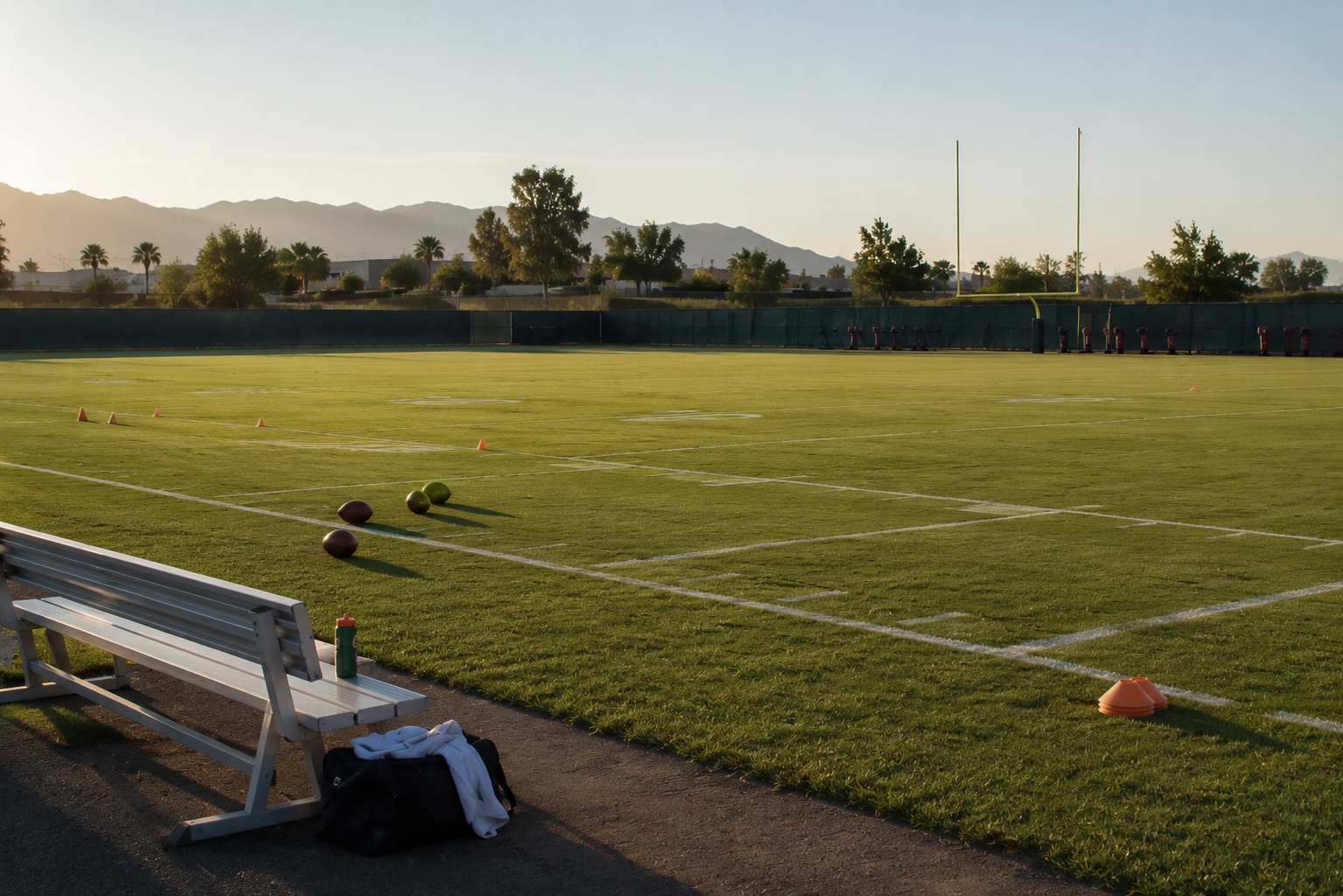 An empty football practice field with cones and footballs near the sideline.
