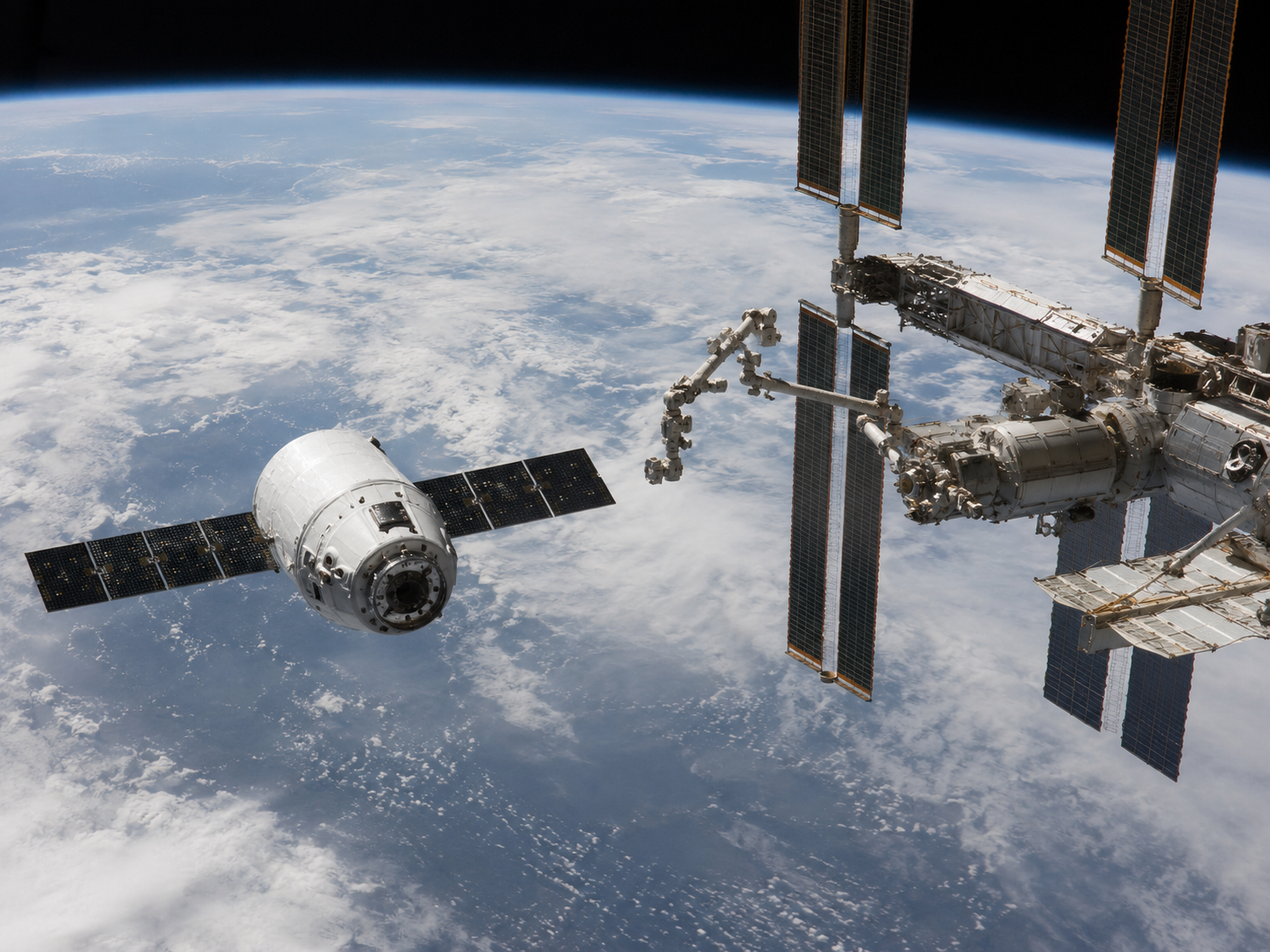 A cargo spacecraft approaches a space station above Earth.