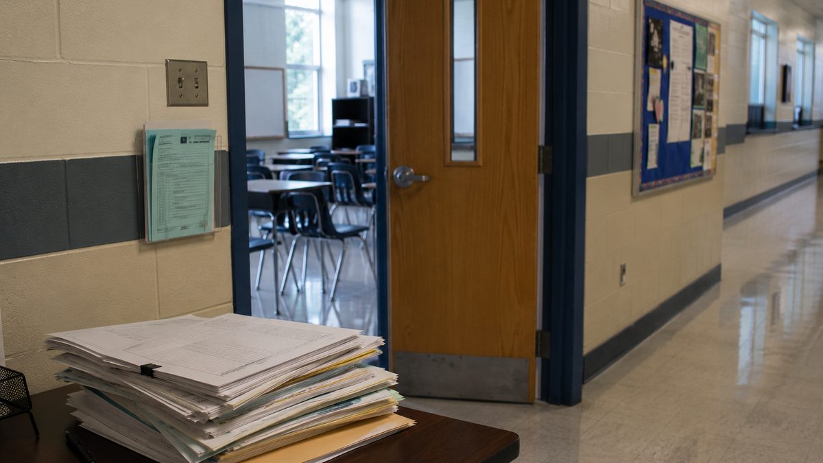 Quiet public school hallway with unreadable education forms on a desk.
