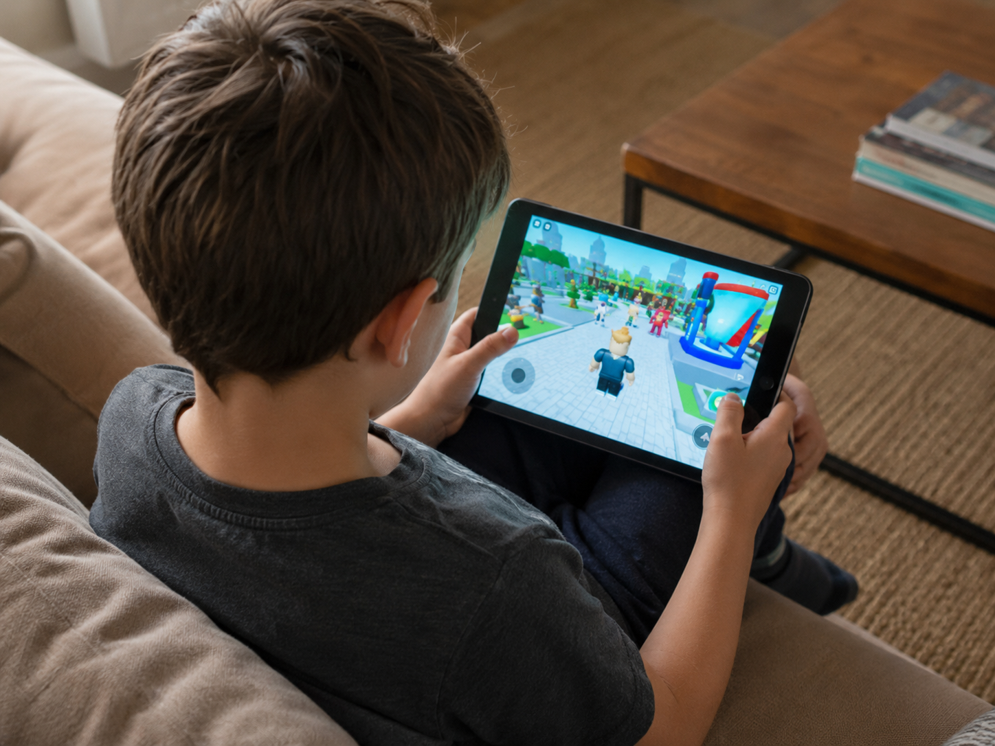 A parent watches near a child's gaming setup while reviewing online safety controls.
