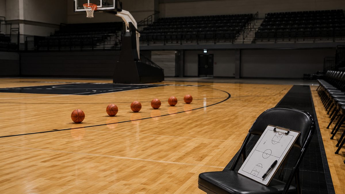 Basketballs line the three-point arc on an empty practice court.