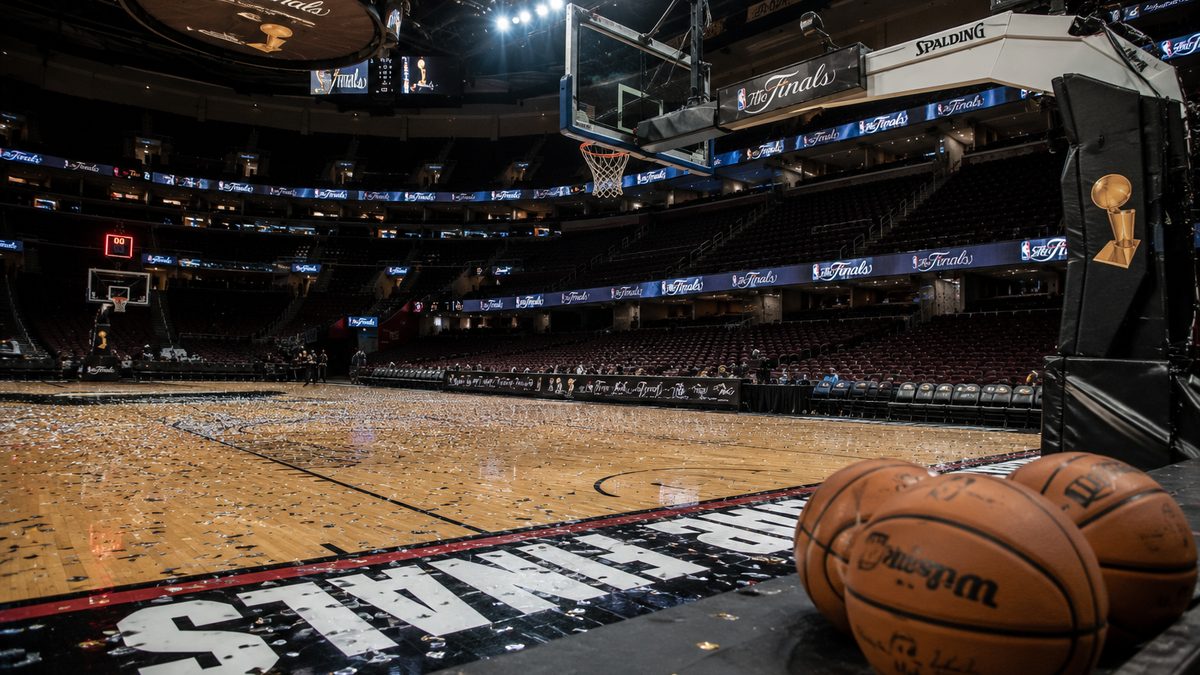 An empty professional basketball arena court lit for a championship game, with basketballs near the sideline and no visible team logos.