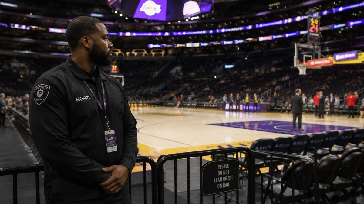 Arena security stands near a courtside barrier before a basketball game.