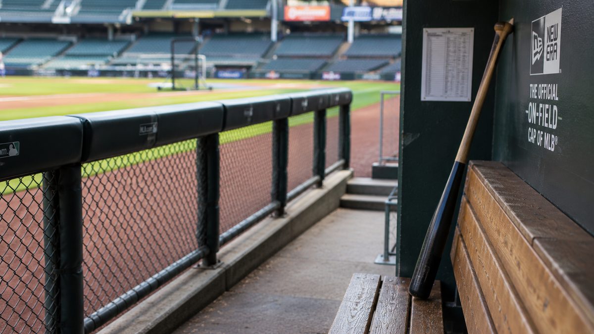 A baseball bat leans near an empty dugout before a game.