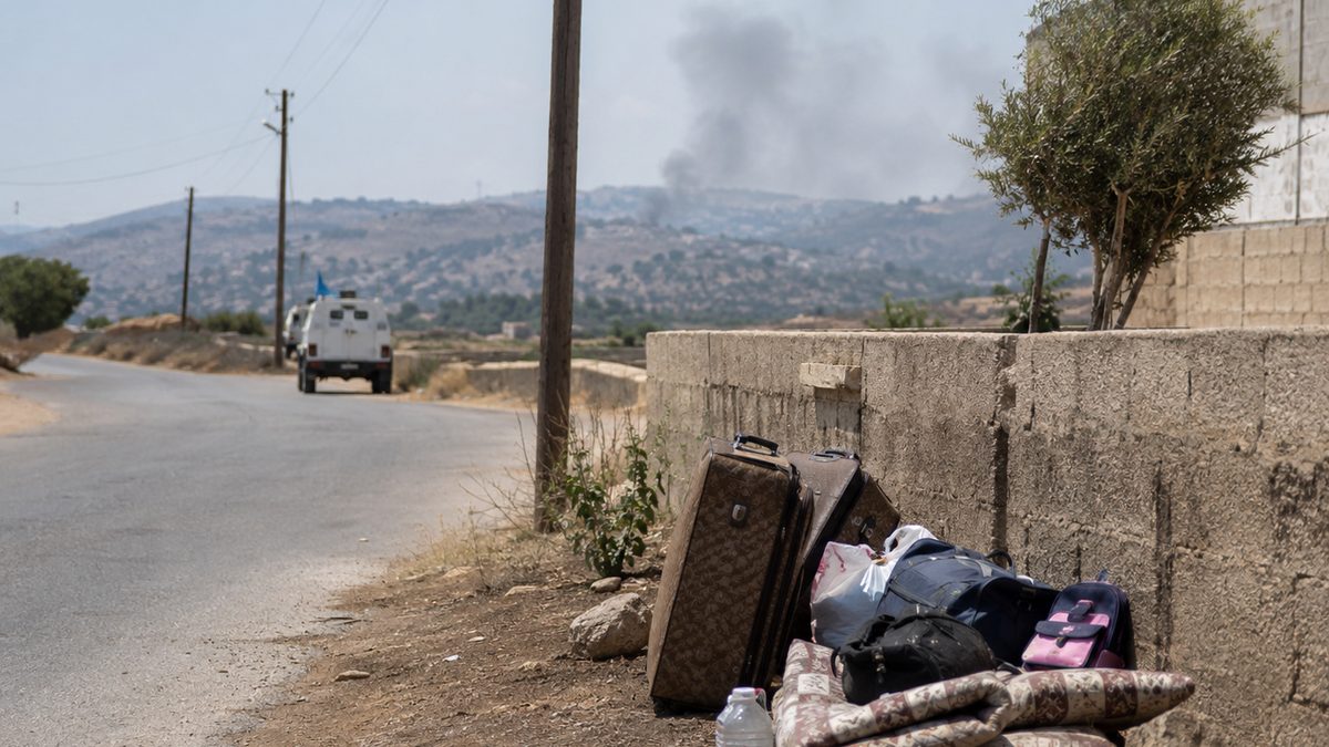 A quiet road near a conflict-affected border area with smoke in the distance.