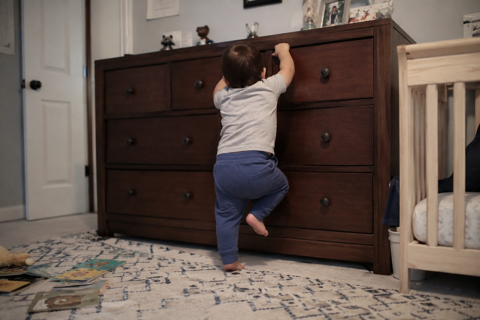 A dresser anchored to a wall in a softly lit bedroom.