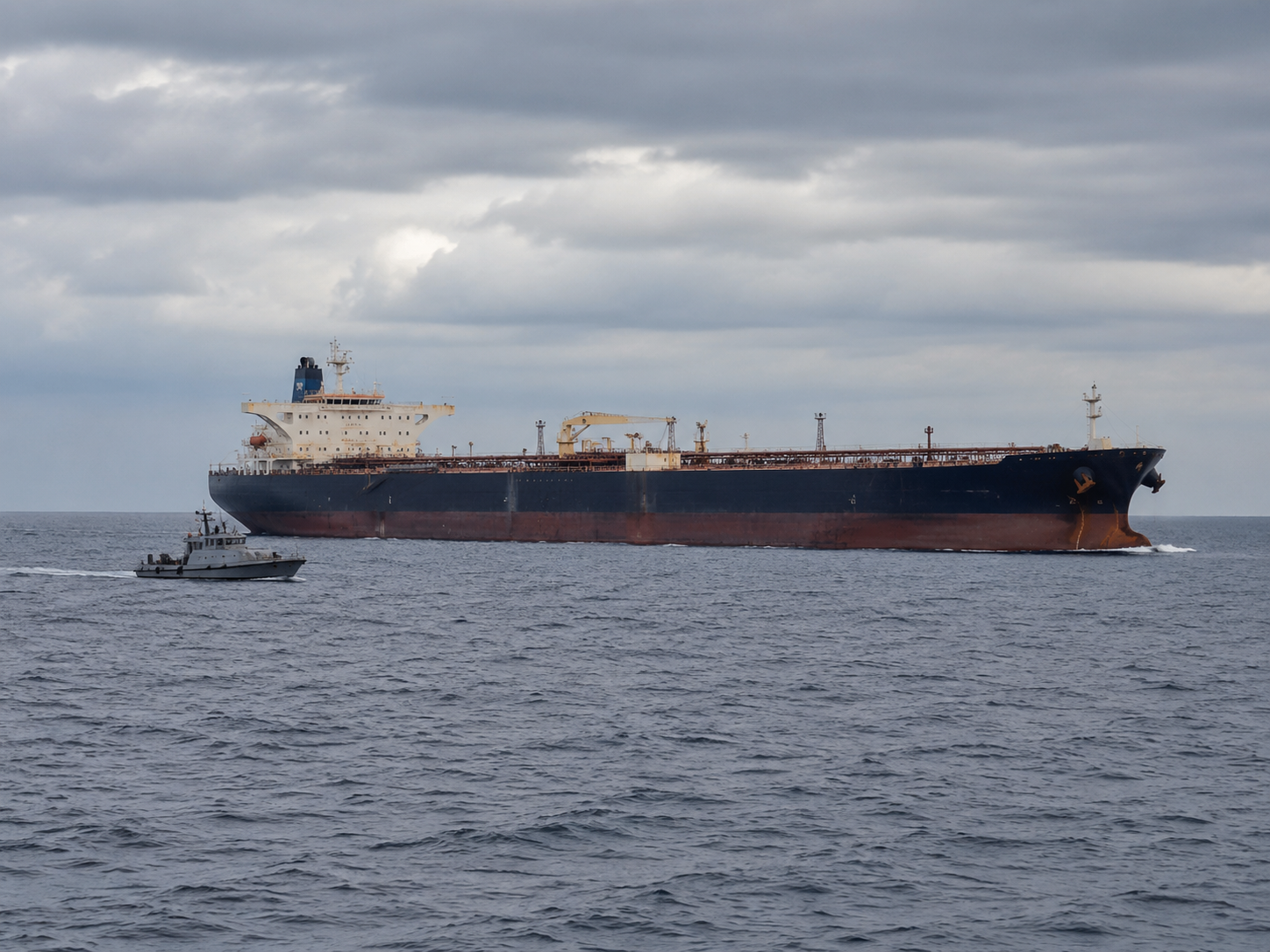 A patrol vessel moves near an oil tanker at sea.