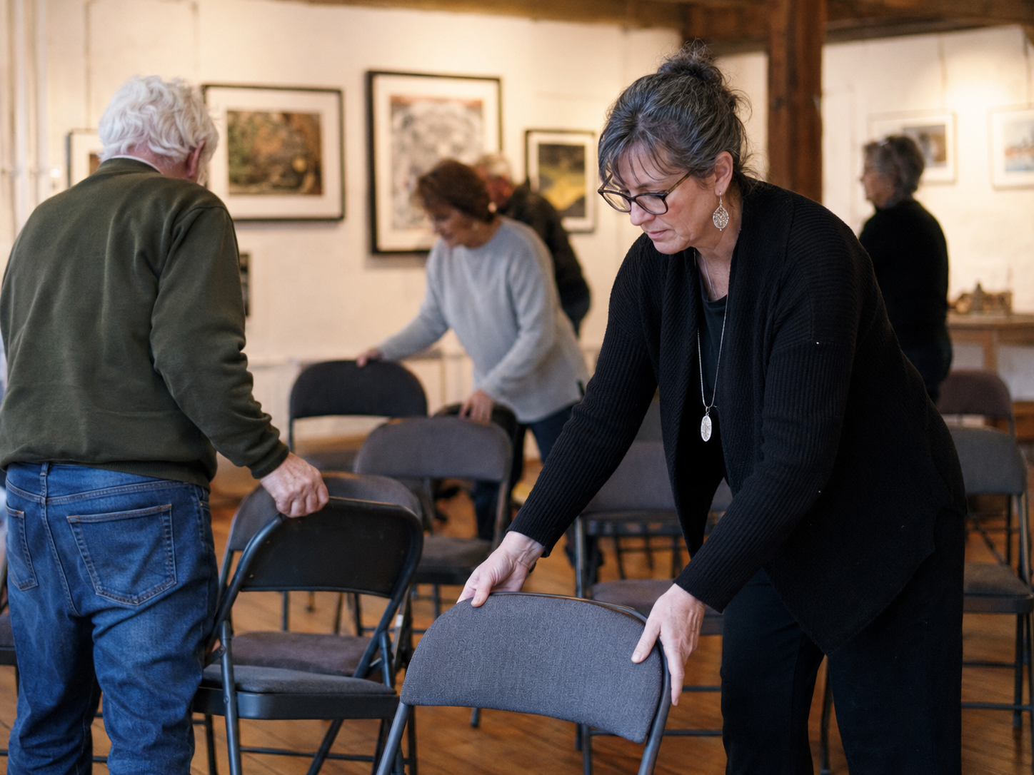 People prepare a small community arts space before a public event.