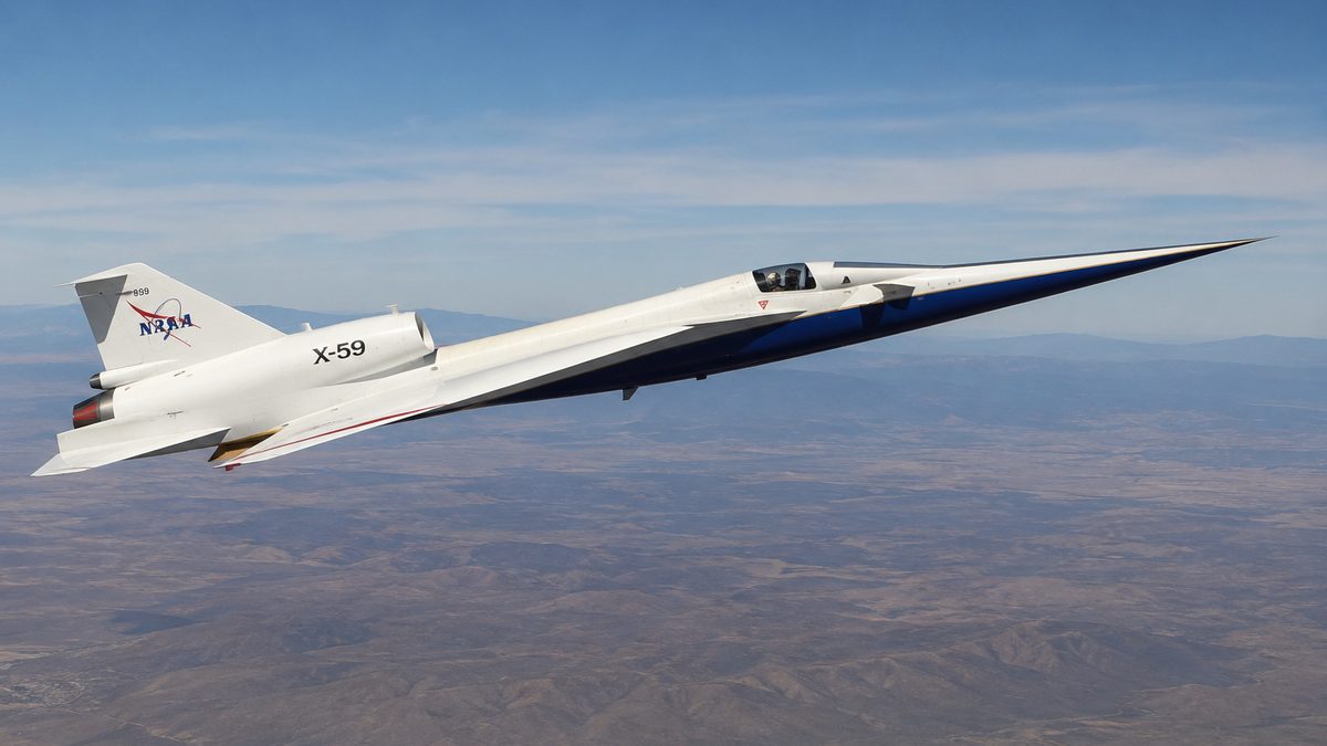 A slender experimental supersonic aircraft flies over a desert test range.