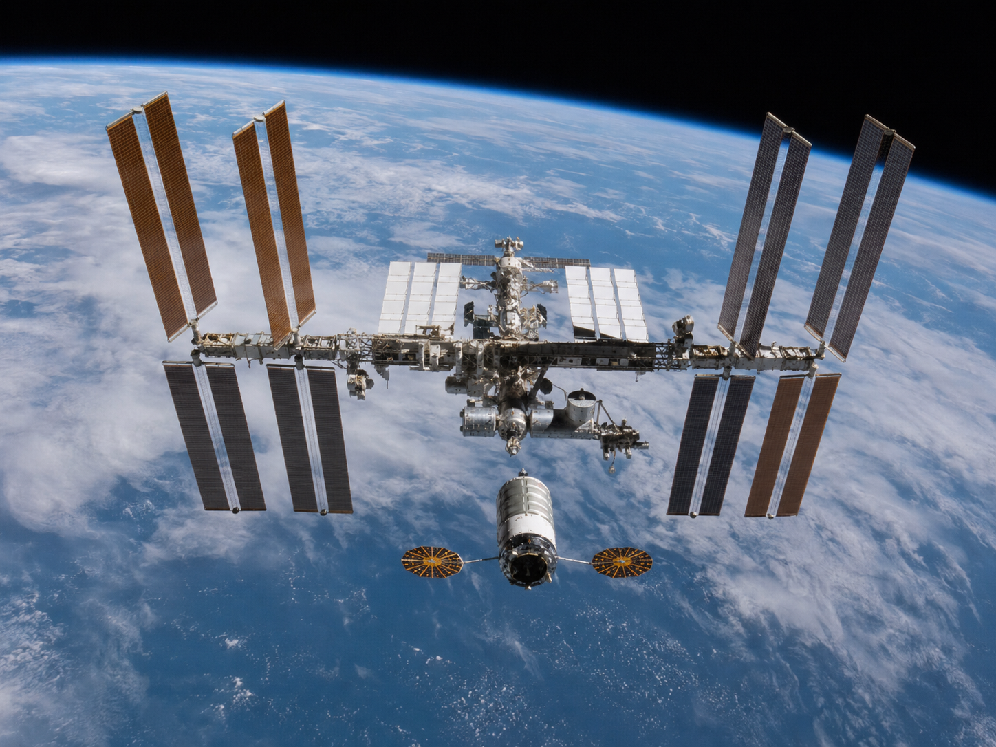A cargo spacecraft approaches the International Space Station above Earth.