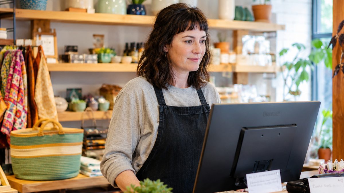 Laptop with a generic chart beside a notebook, with storefronts blurred outside.